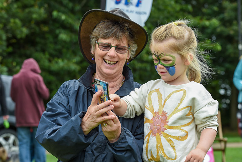 A woman showing her grandchild something on her phone during a community event.