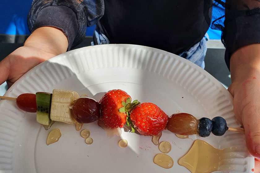 A fruit kebab on a plastic plate