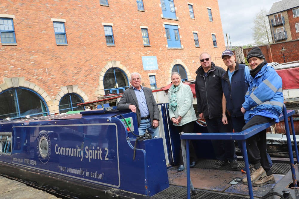 Five people standing on a moored boat smiling