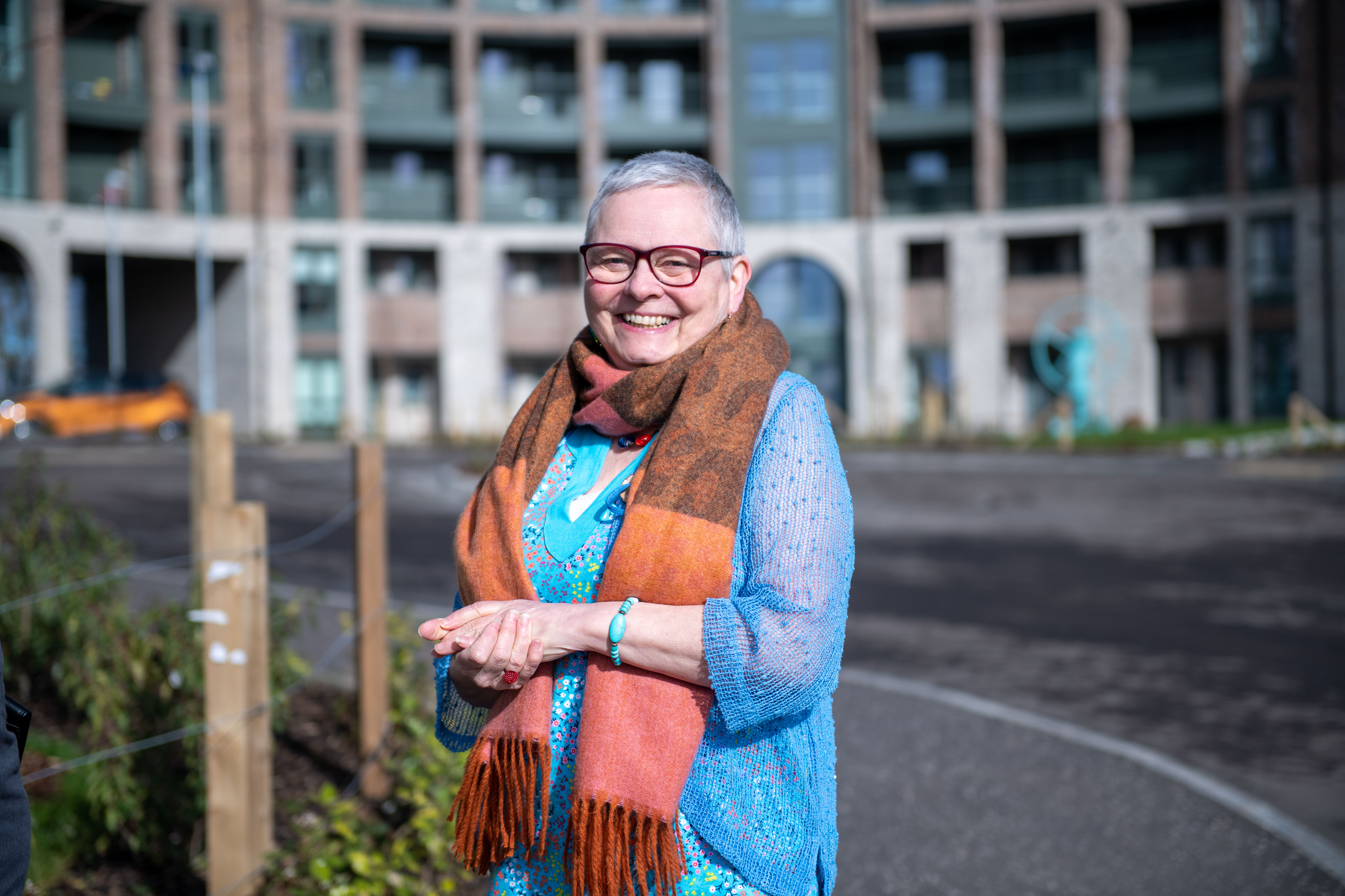 A woman smiling in front of a block of flats