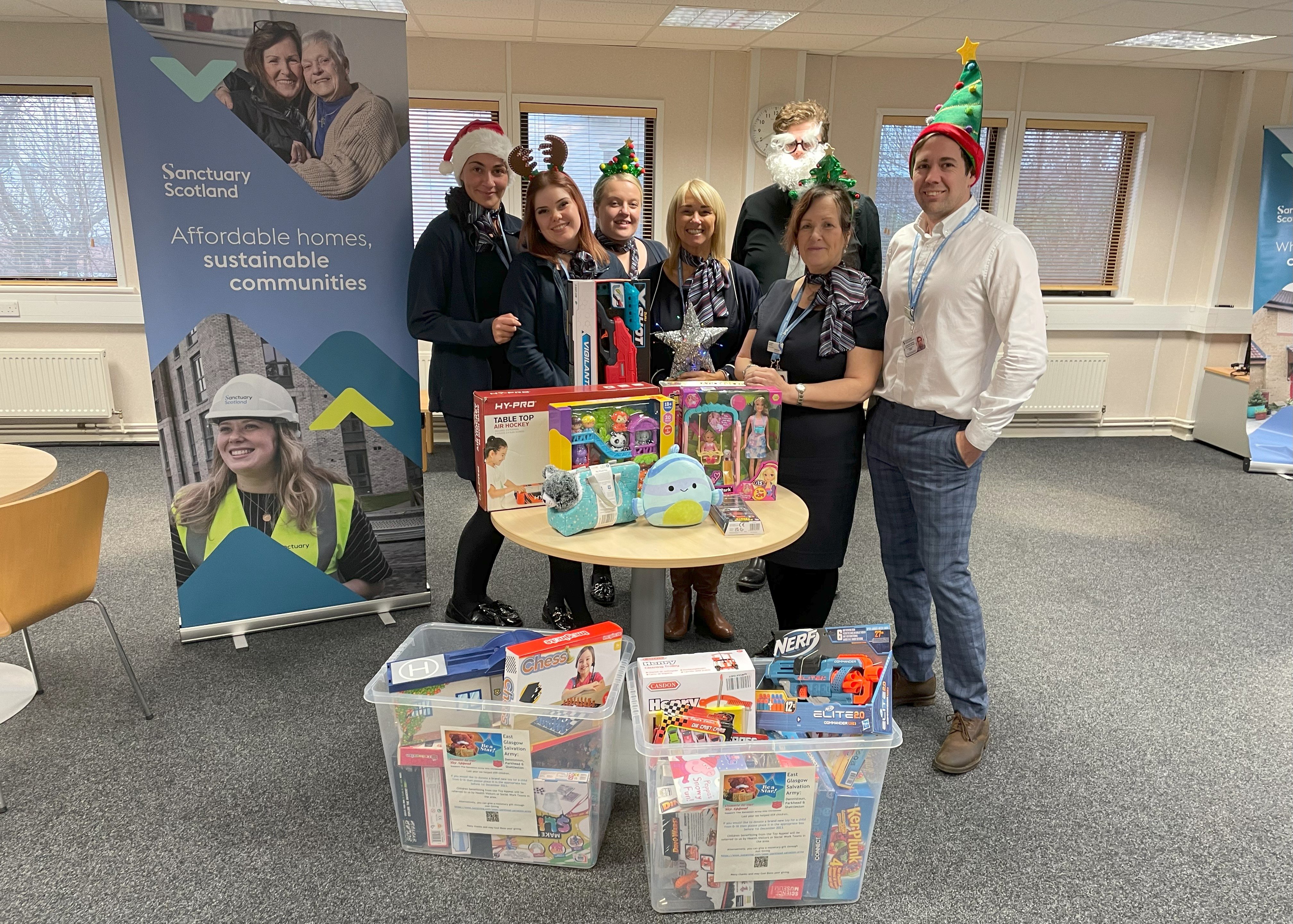 A group of people standing behind a selection of toys