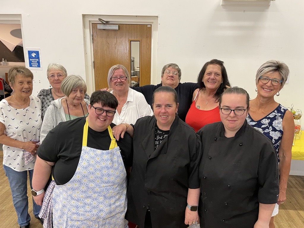 A group of people standing in a community centre smiling