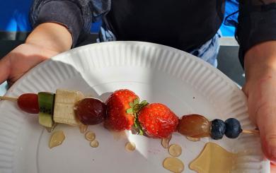 A fruit kebab on a plastic plate