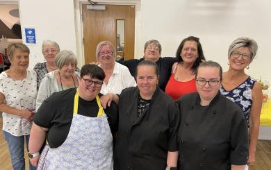 A group of people standing in a community centre smiling