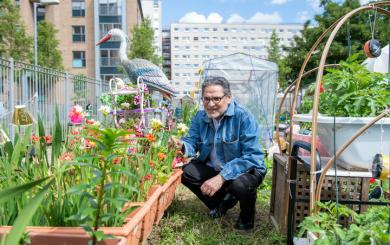 A man kneeling down and smiling in a garden