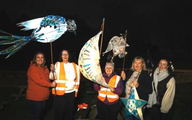 A group of people stood in the dark wearing warm clothes holding their lanterns