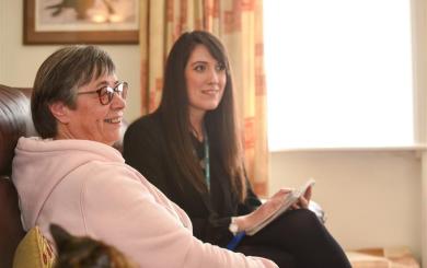 A Housing Officer and a resident sat on a sofa together in the residents home