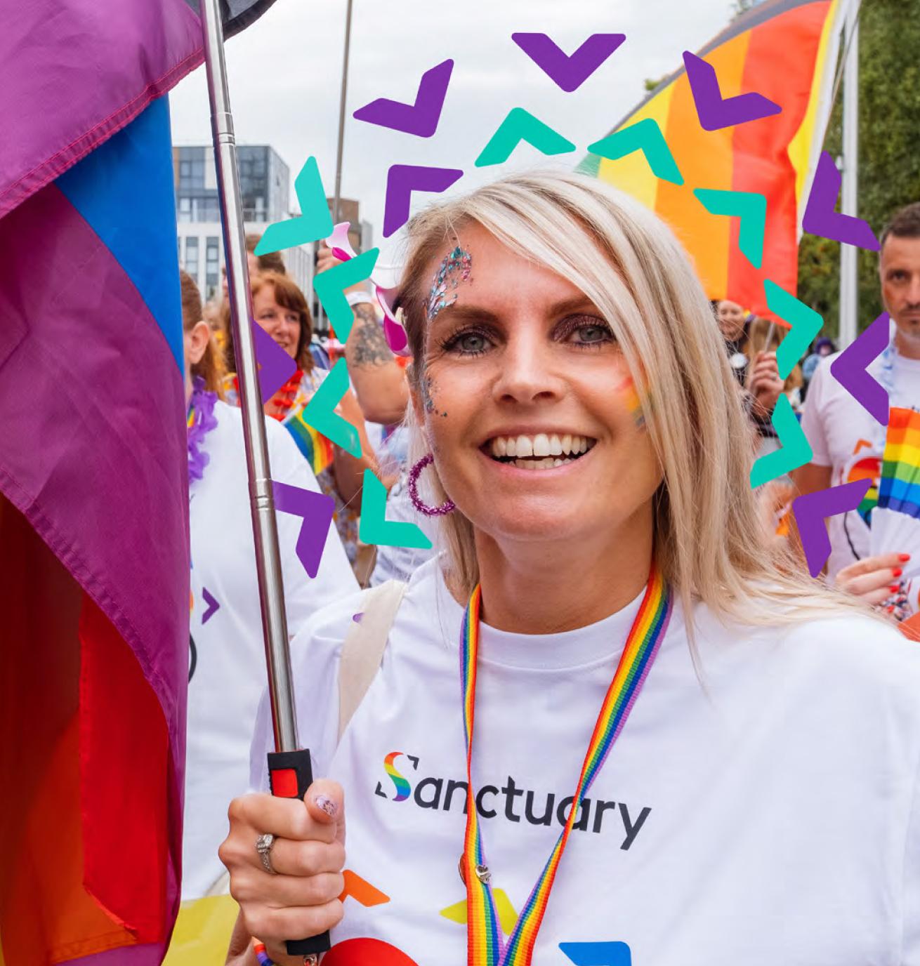 Sanctuary staff and residents wearing white shirts with rainbow hearts on carrying rainbow flags taking part in a march for a PRIDE event