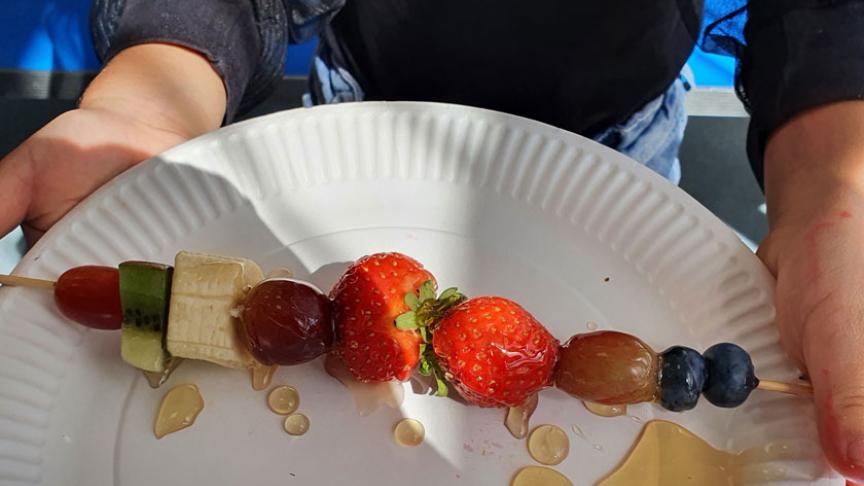 A fruit kebab on a plastic plate