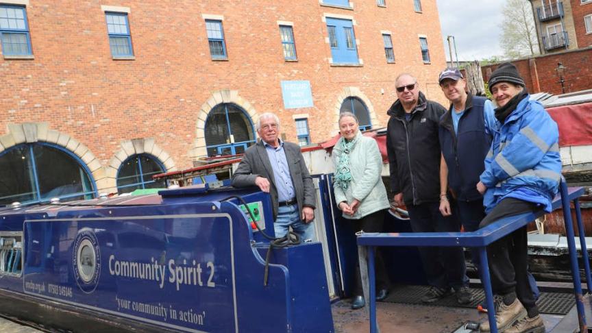 Five people standing on a moored boat smiling