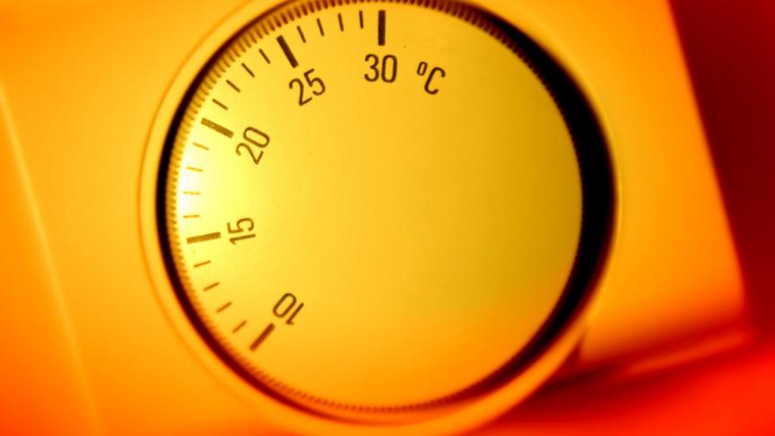 A thermostat is shown surrounded by a warm orange glow