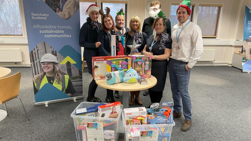 A group of people standing behind a selection of toys