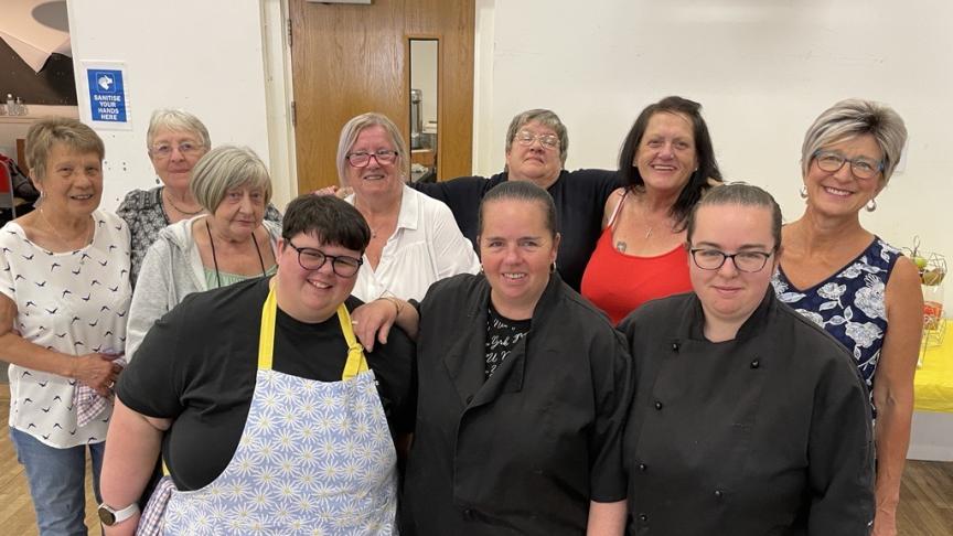 A group of people standing in a community centre smiling