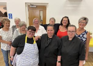 A group of people standing in a community centre smiling