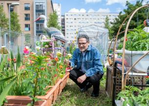 A man kneeling down and smiling in a garden