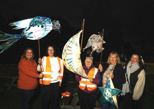 A group of people stood in the dark wearing warm clothes holding their lanterns